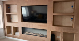 Media wall design with built-in TV and shelving by MSP Plastering Solutions